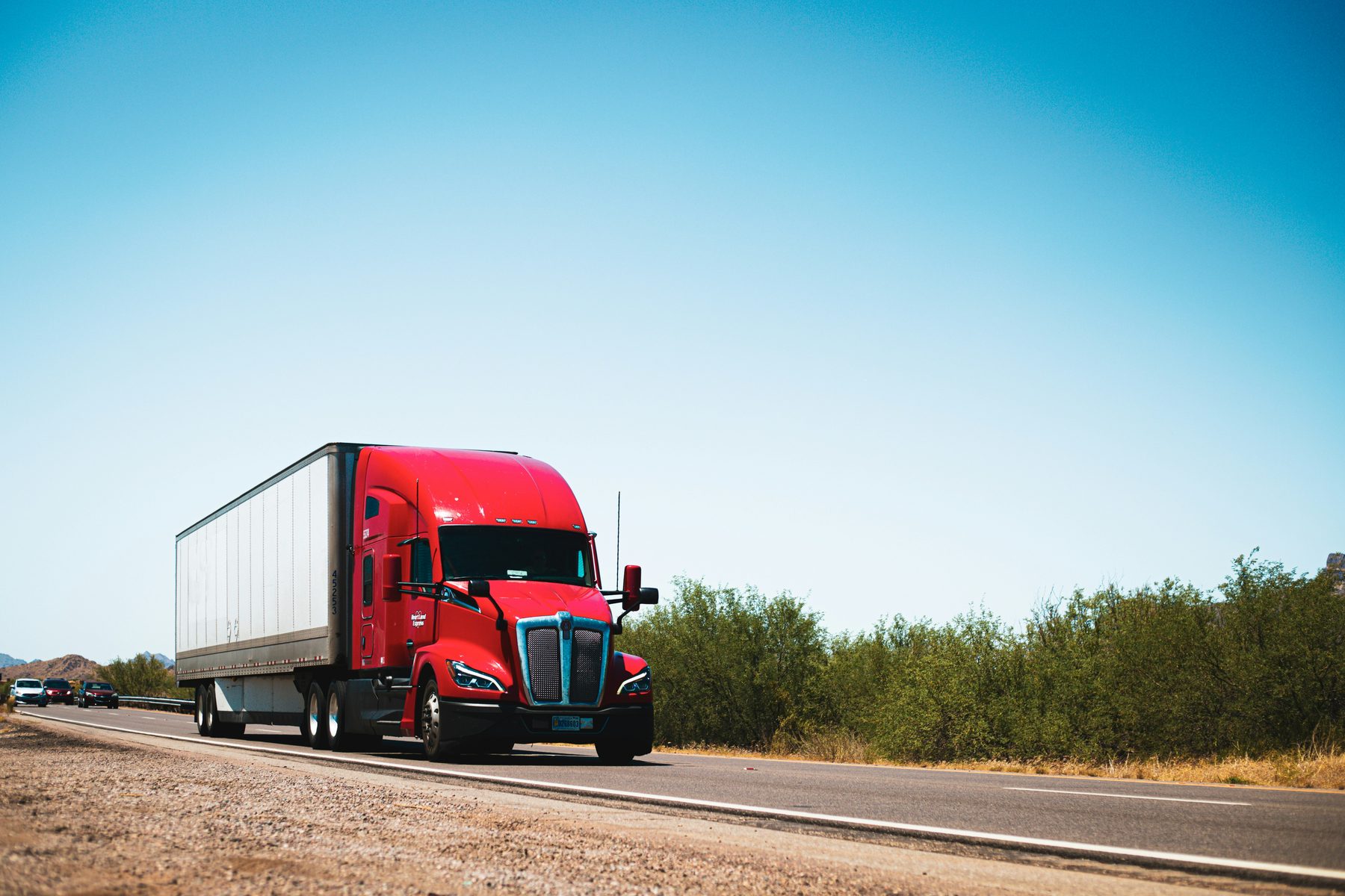 Red semi truck moving along an open highway